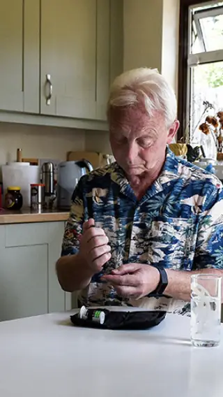 Man checking his blood sugar levels in a kitchen